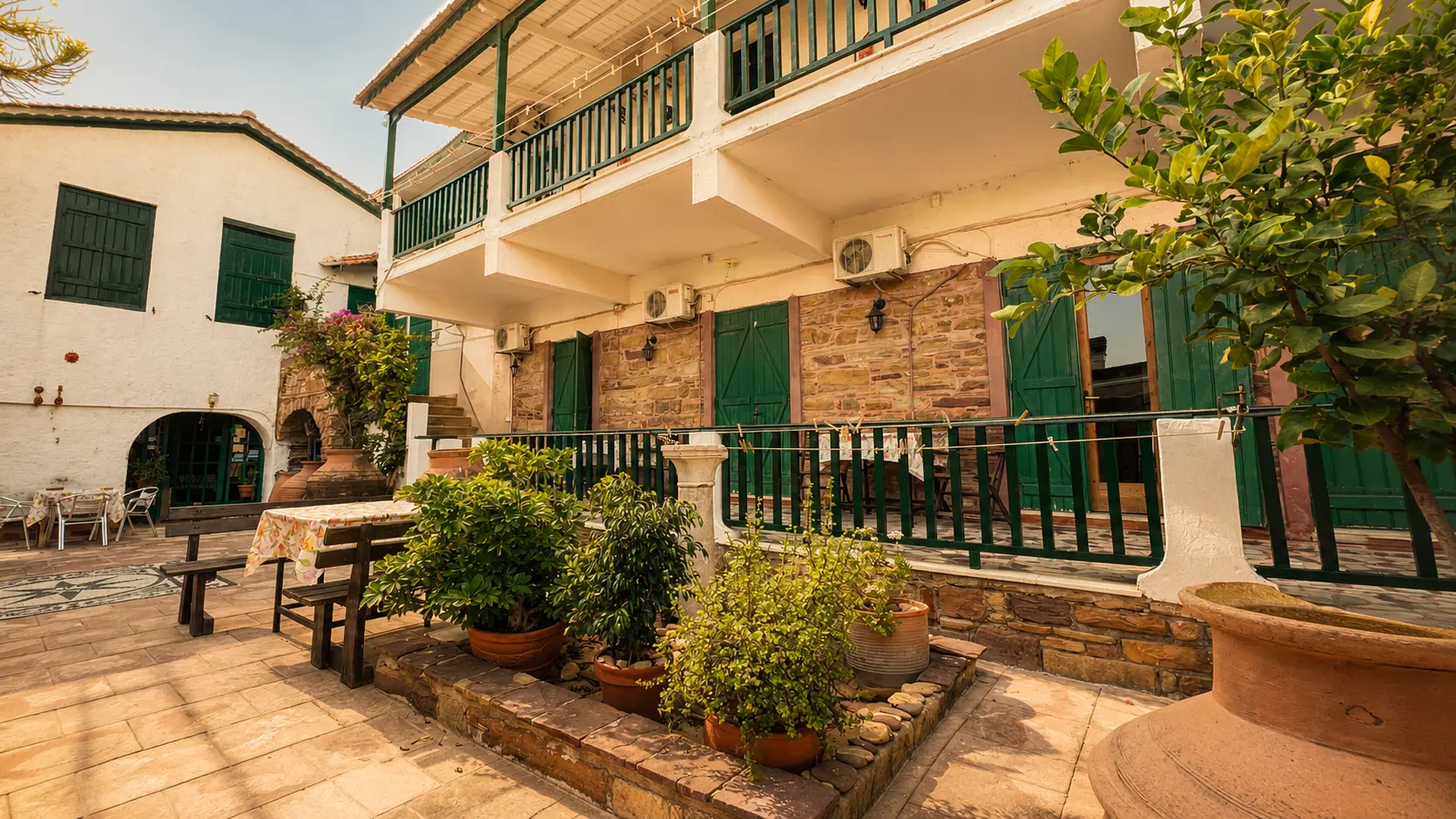 Το σπίτι και η σκιερή βεράντα του με θέα στα περιβόλια